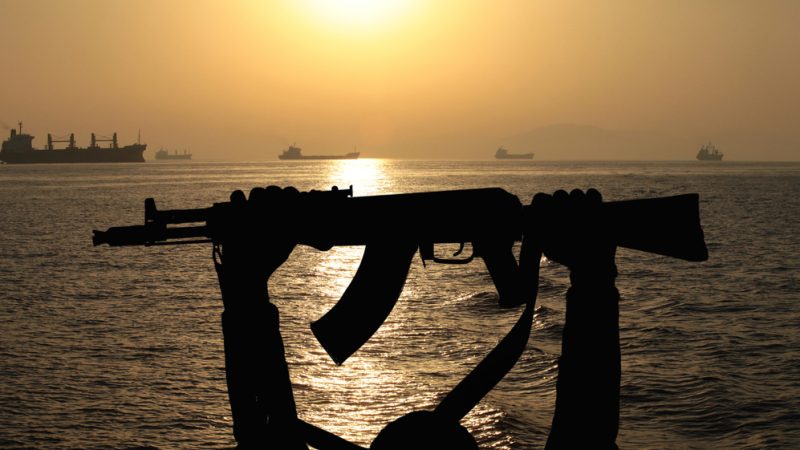 Silhouet van AK-47 met op achtergrond een schip